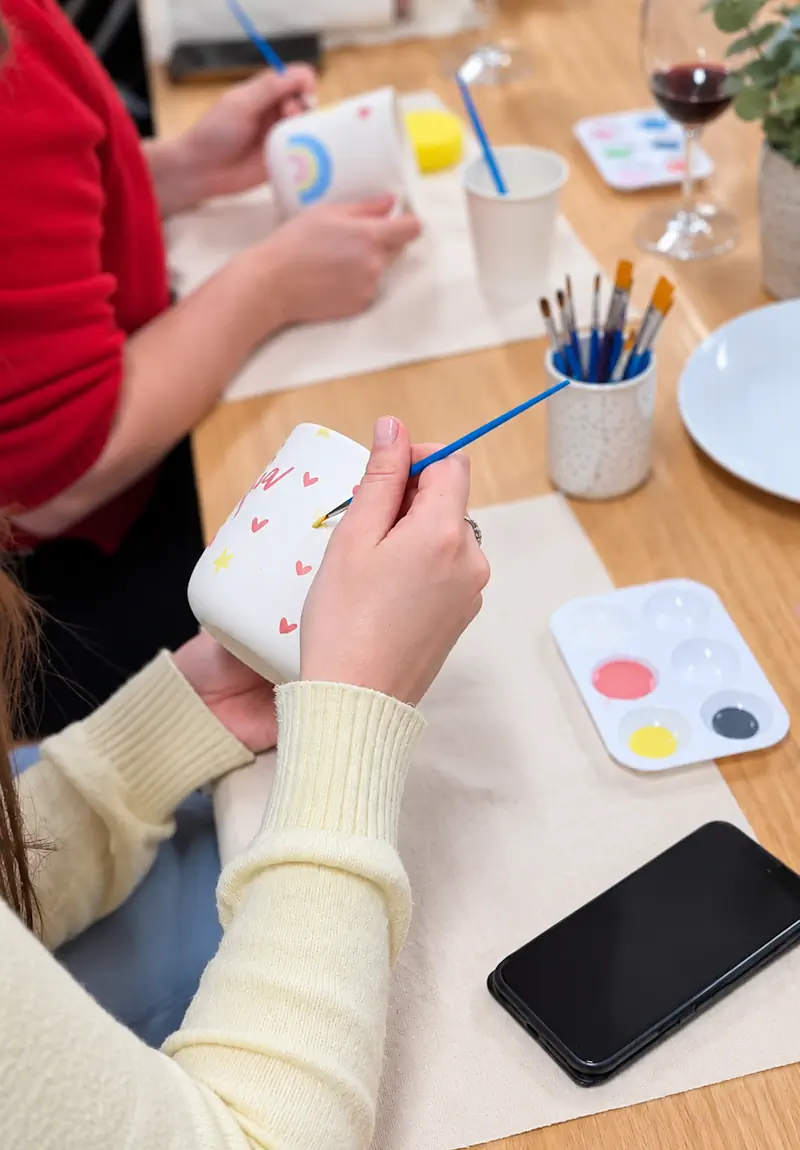 Team member painting a ceramic mug during a corporate pottery workshop in Melbourne